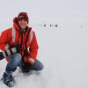 Cassandra Brooks posing for a photo in Antarctica with penguins behind her.