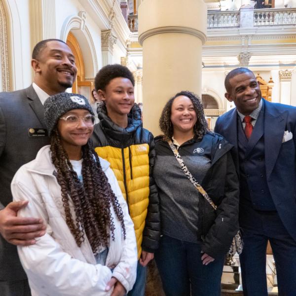 Sen. James Coleman, vice chair of the Colorado Black Caucus, left, and his family poses with Deion Sanders after a breakfast meeting with the Caucus at the state Capitol